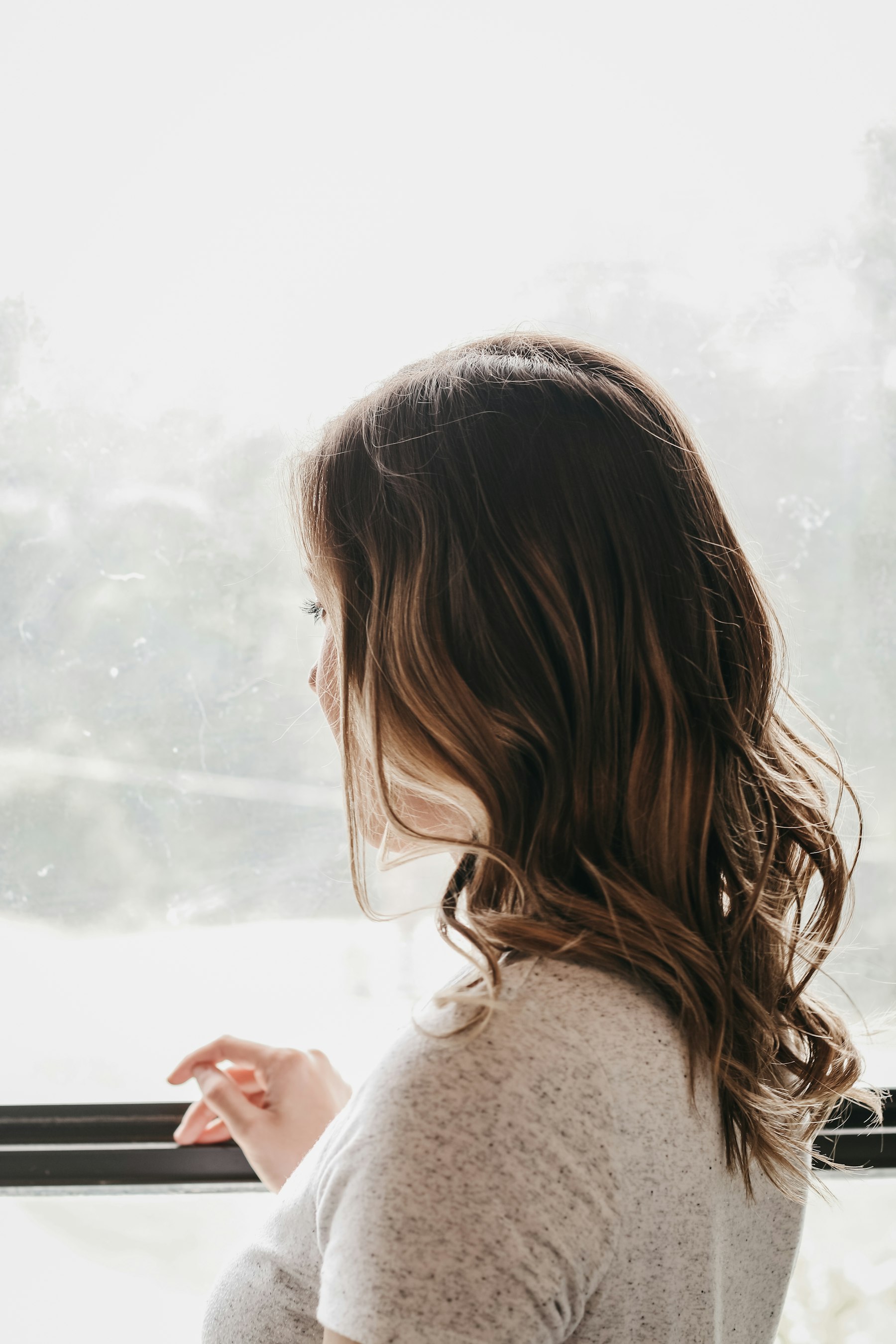 A woman looking out through a window in warm natural light
