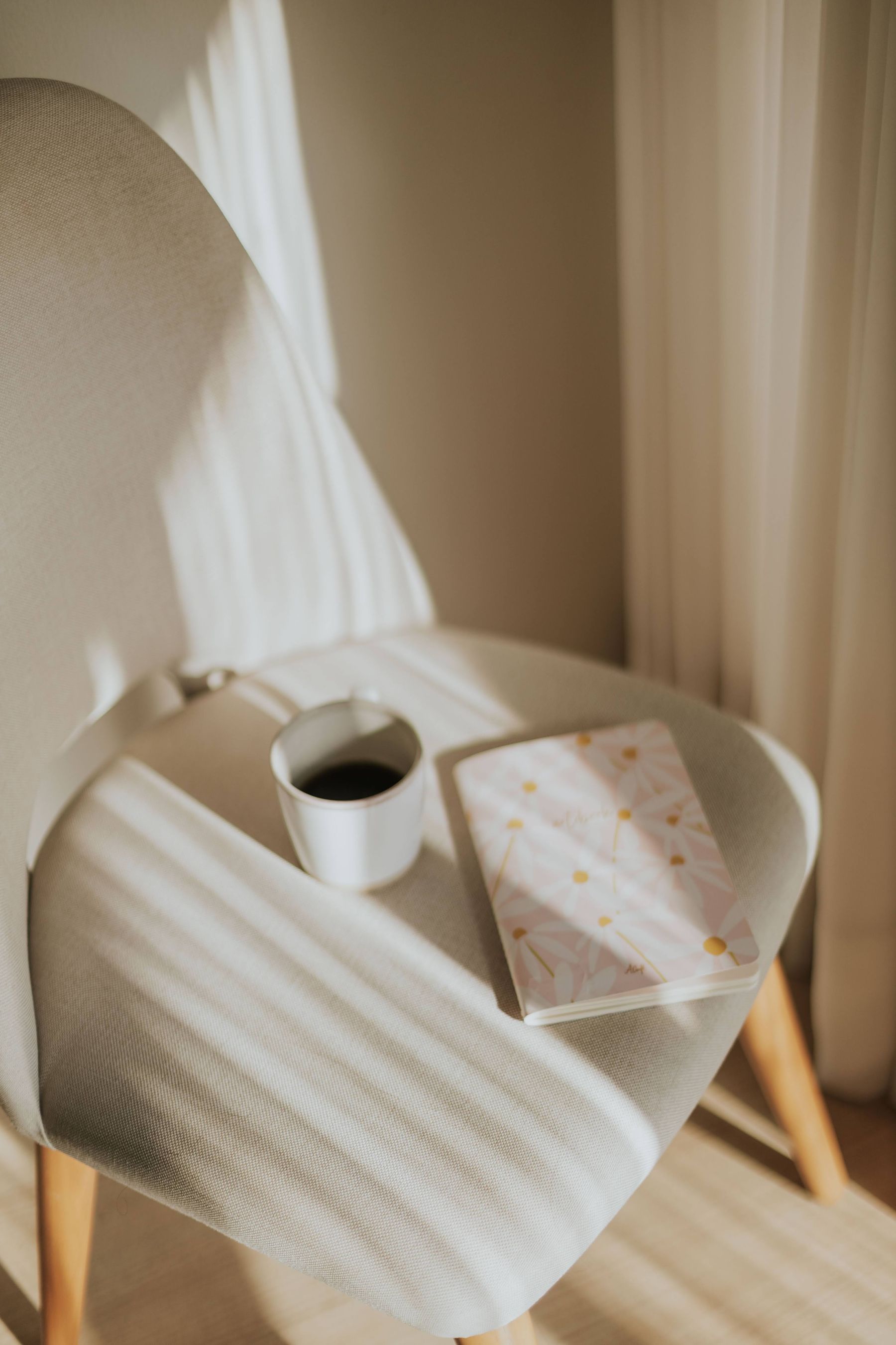 A sunlit desk with coffee and a notebook, warm shadows across the paper