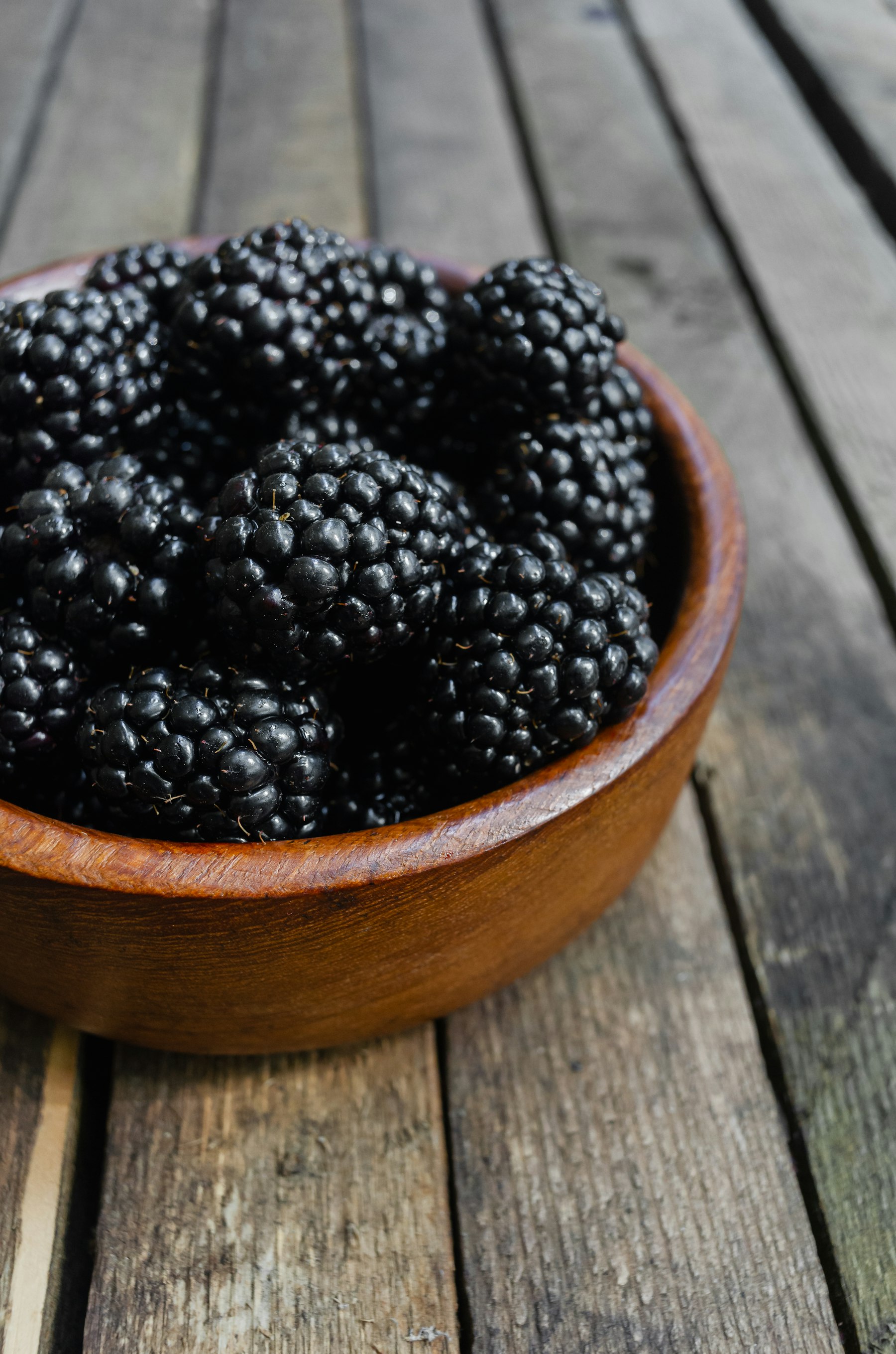 Deep purple berries heaped in a warm wooden bowl